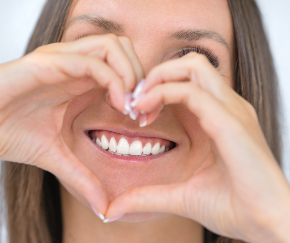 Women smiling and making a heart shape with her hand 